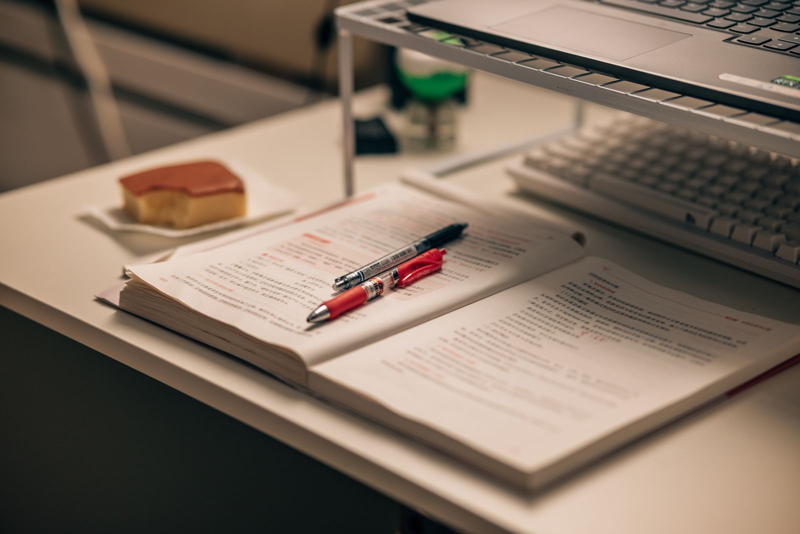 Open RBT study manual with highlighted notes, pens and a laptop on a desk — preparing for the 2026 RBT exam